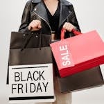 A woman in a leather jacket holds Black Friday shopping bags indoors Perfect for sale promotions